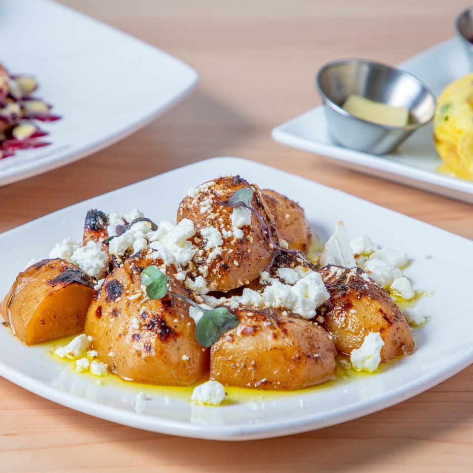 Roasted potatoes topped with crumbled feta cheese and herbs, drizzled with olive oil.